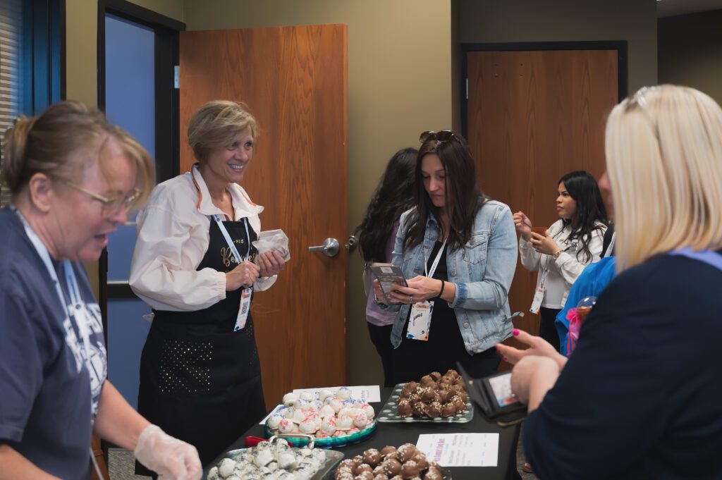 Women chatting and picking out sweets from a table filled with homemade chocolate treats and truffles at the Sisterhood event.