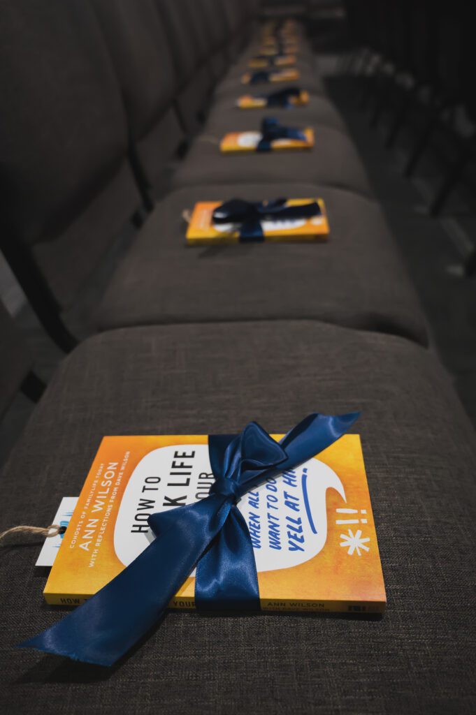 Close-up of Ann Wilson’s book ‘A Woman You Love’ placed on a chair with a pink ribbon, ready for attendees at the Sisterhood 2025 event.