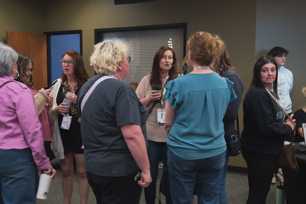 A group of women chatting in a heartfelt moment of connection, sharing laughter and love at Sisterhood 2025.