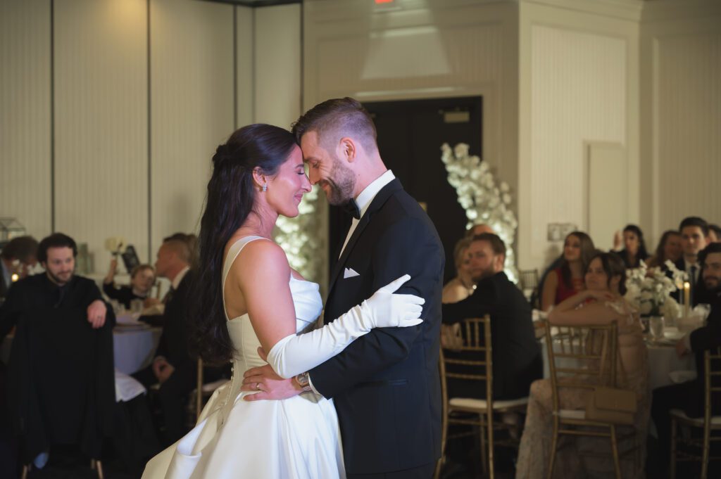 Bride and groom embrace with foreheads touching during their first dance.